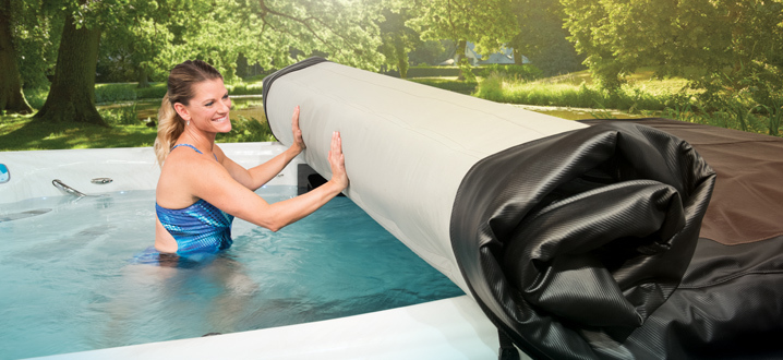 woman rolling up the axis cover system while inside her swim spa